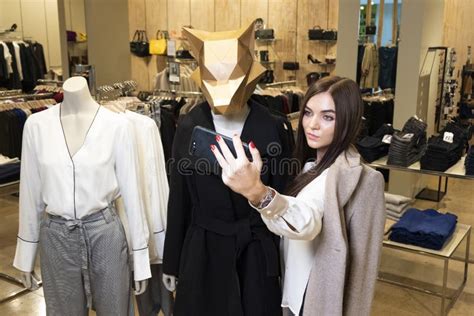 beautiful brunette girl takes a picture of herself on the phone in a clothing store selfies