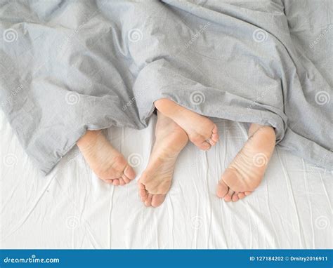 Feet Of Couple Sleeping Side By Side In Comfortable Bed Close Up Of