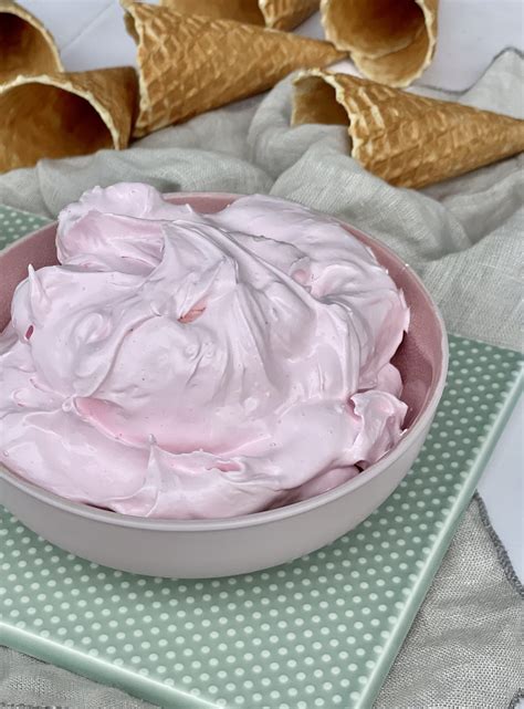 A Bowl Filled With Pink Whipped Cream Next To Two Cones On Top Of A Table