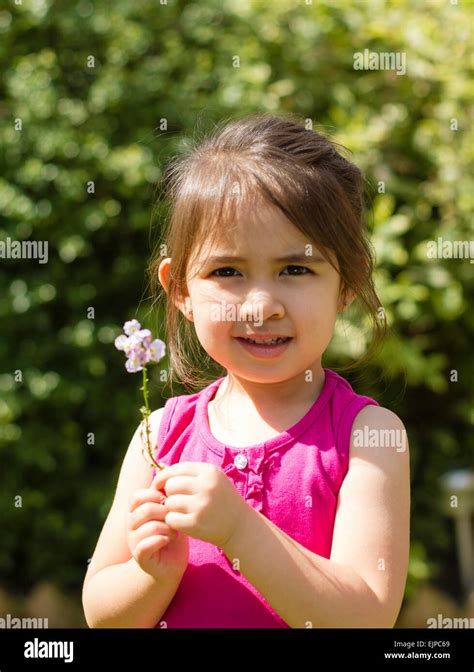 Little Girl Of Caucasion Chinese Holding A Flower In A Suburban Garden