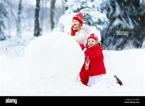 Children Build Snowman Kids Building Snow Man Playing Outdoors On