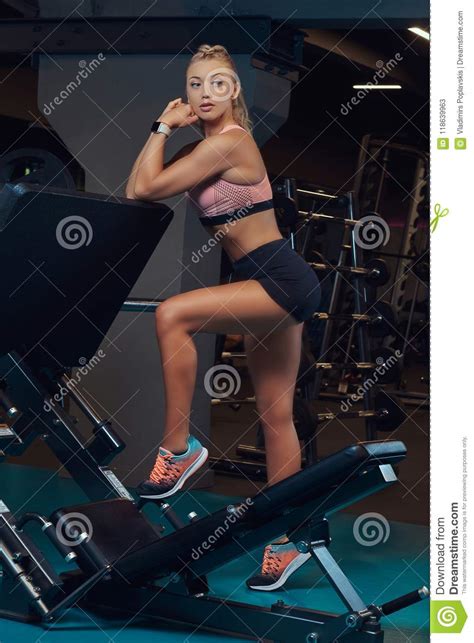 Athletic Blonde Woman In Sportswear Posing Near The Legs Press Machine