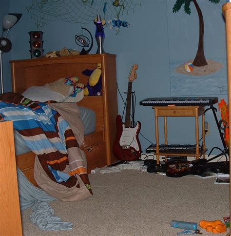 A Messy Bedroom With Blue Walls And Palm Trees On The Wall