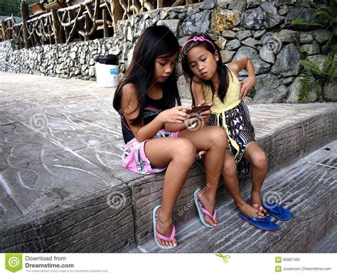 Young Girls Play A Video Game On A Smartphone While Sitting On A Set Of