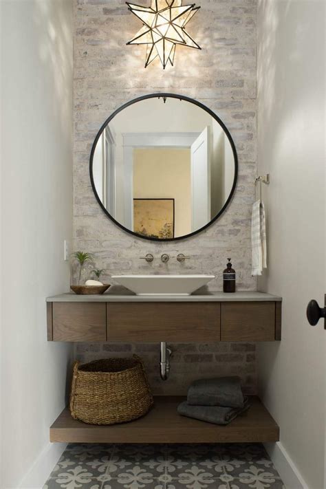 A Bathroom With A Round Mirror Above The Sink And A Basket On The Floor