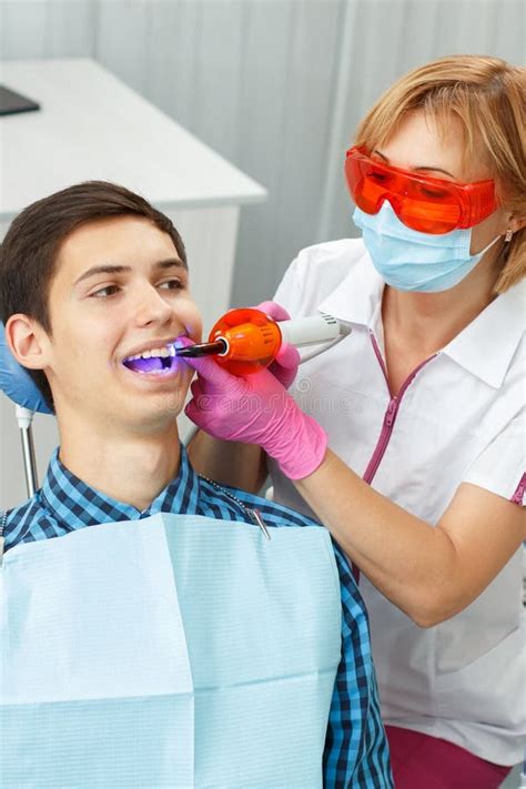 Beautiful Woman Dentist Treating A Patient Teeth In Dental Office Stock