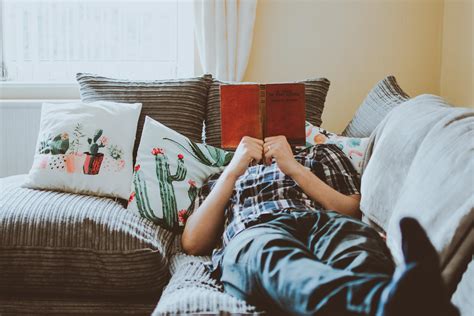 personne allongée sur le canapé pendant la lecture du livre · photo gratuite