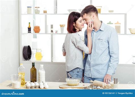 Happy Couple In Love Cooking Dough And Kissing In Kitchen Stock Image