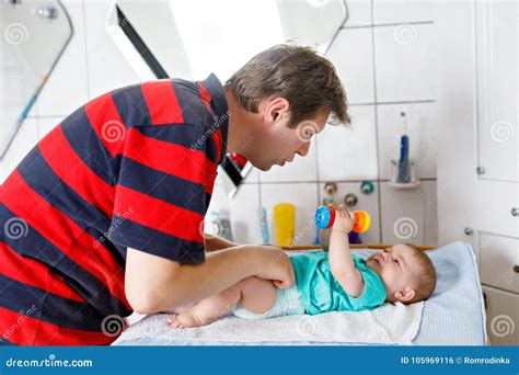 Loving Father Changing Diaper Of His Newborn Baby Daughter Stock Photo