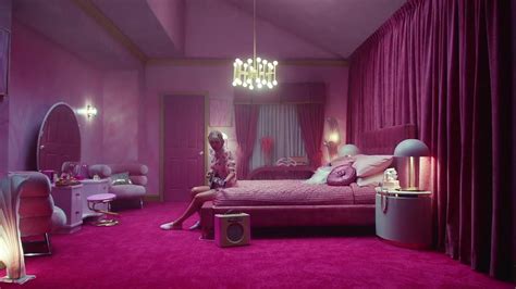 A Woman Sitting On Top Of A Bed In A Room With Pink Walls And Curtains