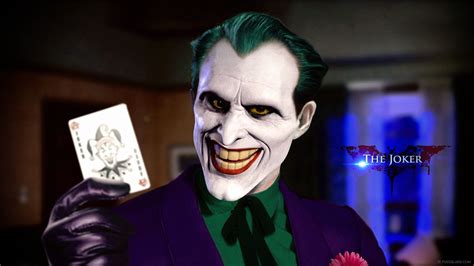 The Joker Is Holding Up A Card In His Hand
