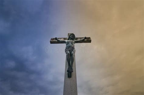 Jesus Christ On The Cross Against Dramatic Cloudy Sky At Sunset