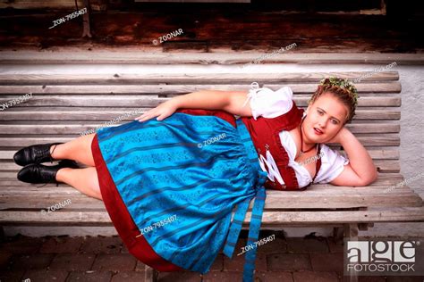 bavarian chubby girl with big bust in dirndl and plaits with elaborate floral wreath resting on