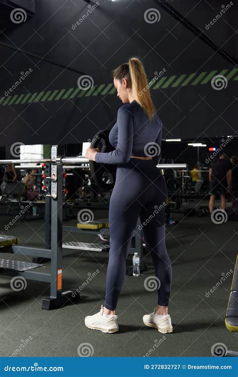 One Adult Caucasian Woman Female Athlete Putting Weight Plate On The