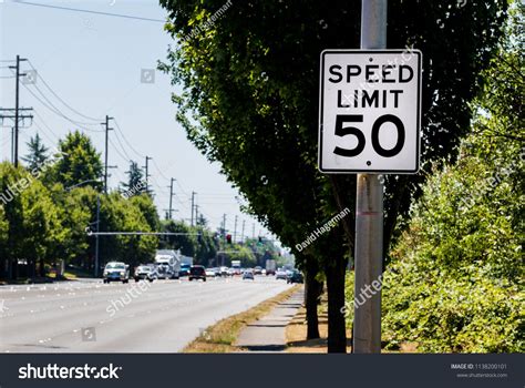 50 Mph Speed Limit Sign On Post With A Road And Tree With