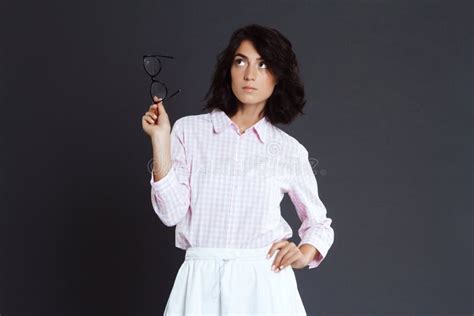 Young Woman Holding Glasses In Hand Posing Over Grey Background Stock