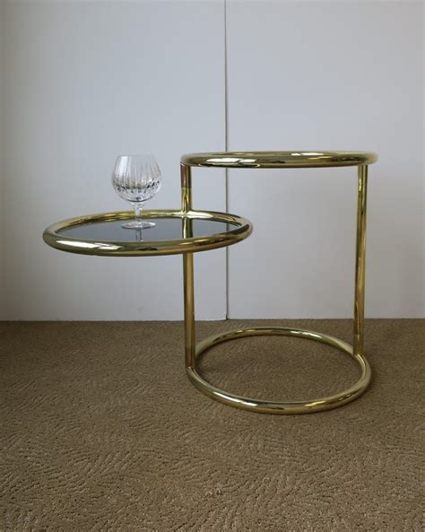 This end table is made from acrylic, stainless steel, and tempered glass for a luxurious take on clear tables. Modern Swivel Round Brass and Glass Side Table After Milo Baughman, ca. 1970s at 1stdibs