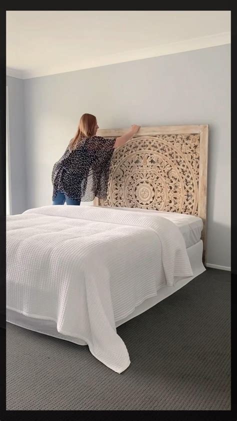 a woman standing on top of a bed next to a white comforter and pillows