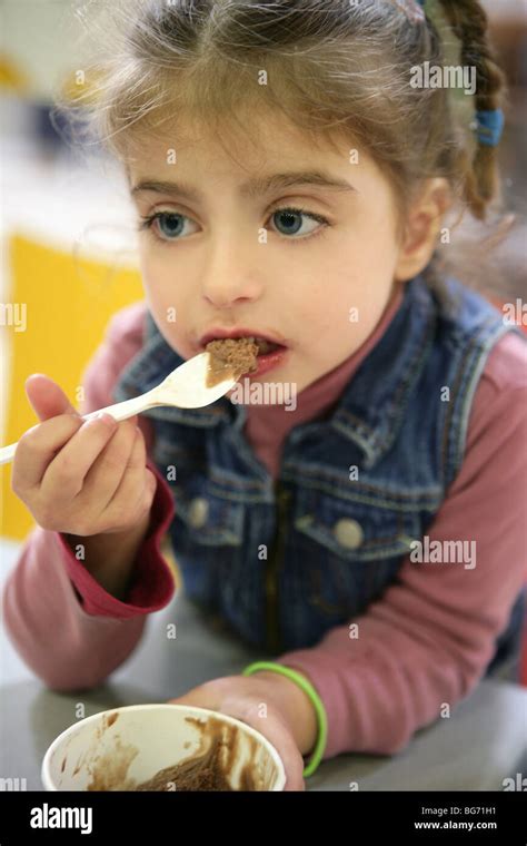 Sweet Girl Gets Dirty Eating Chocolate Ice Cream With Spoon Stock Photo