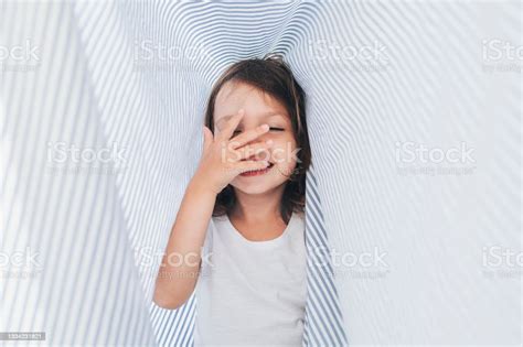 Gadis Kecil Yang Bahagia Menggosok Wajahnya Saat Bersenangsenang Di Bawah Seprai Foto Stok