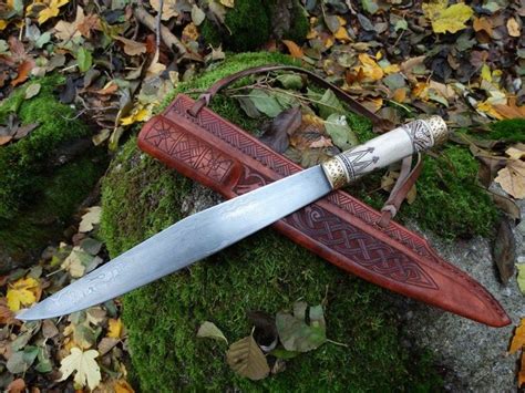 A Large Knife Sitting On Top Of A Moss Covered Rock