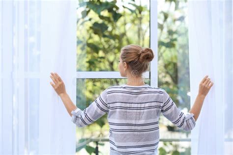 Young Woman Opening Curtains And Looking Out Stock Photo Image Of