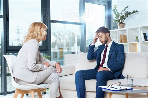 psychologist talking with depressed young patient at psychotherapy - Stock Photo - Dissolve