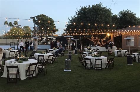 White folding chairs at an outdoor wedding with flowers. Fruitwood Folding Chair Rentals | Wood-n-Crate Designs™