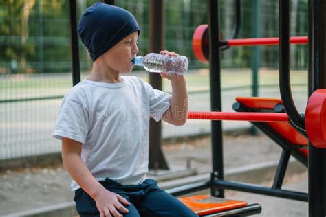 Little Boy Drinking Water Near Outdoor Public Fitness Equipment Stock