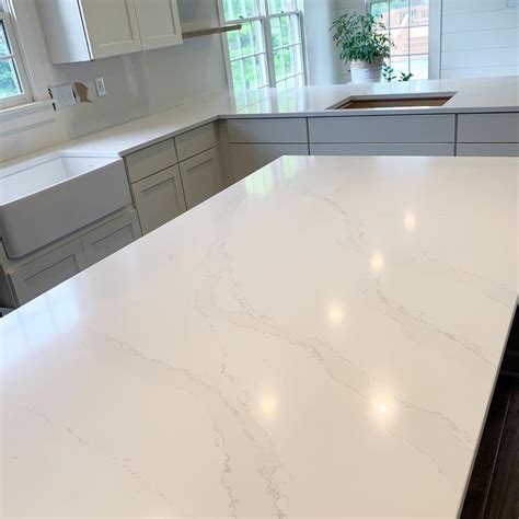 A Large Kitchen With White Cabinets And Marble Counter Tops