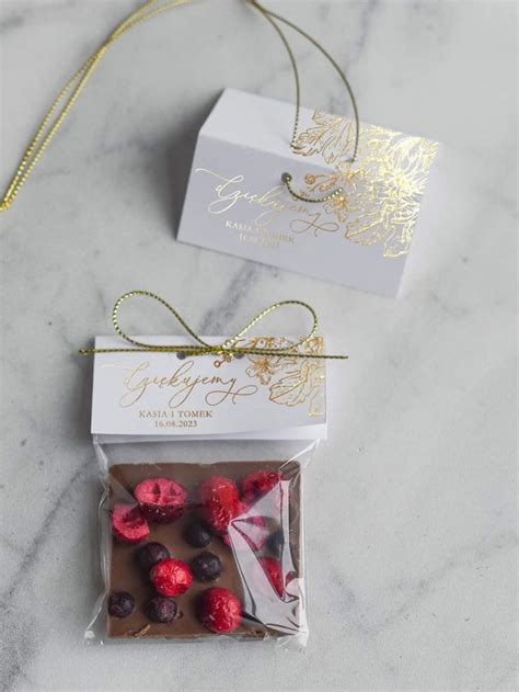 Two Packaged Chocolates With Raspberries In The Middle On A Marble Countertop