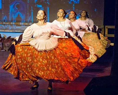 three women in long skirts are dancing on stage