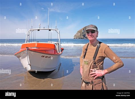 A Dory Fisherman Stands Near His Boat On The Beach At Pacific City