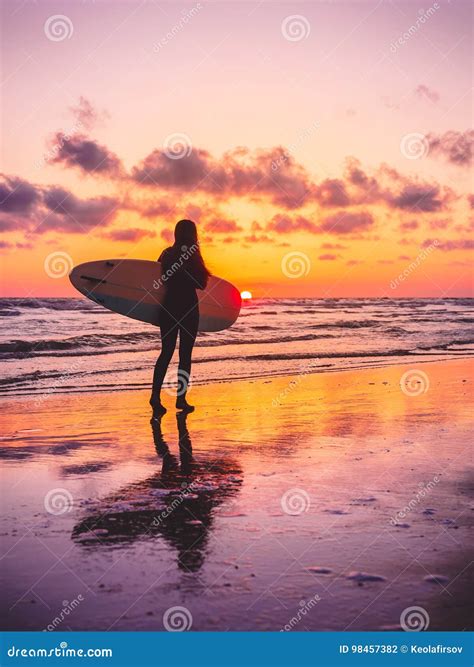 Surf Girl With Surfboard With Warm Sunset Or Sunrise Colors Stock Photo