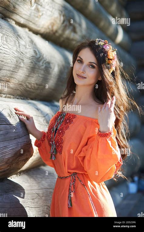 beautiful slavic woman in an orange ethnic dress and a wreath of flowers on her head beautiful