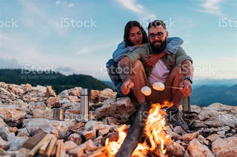 Lovely Young Couple Roasting Marshmallows While Camping In The