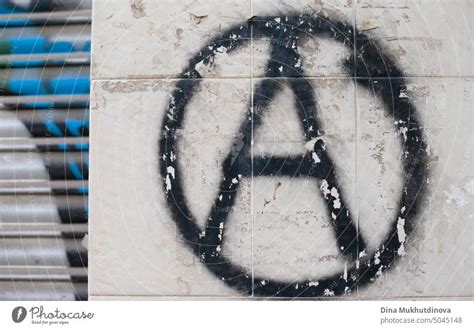 Graffiti On The Wall With A Black Anarchy Symbol Sign On A Gray Wall
