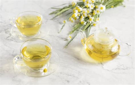 Glass Cups And Teapot With Chamomile Tea On A White Background A