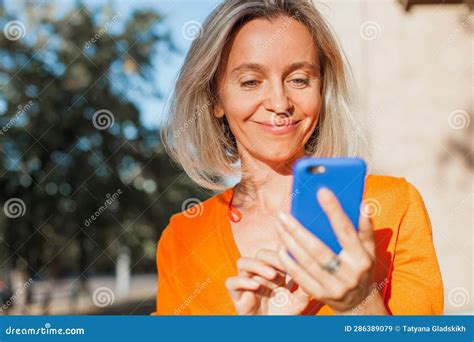 happy middle aged woman outside in city with mobile phone stock image image of portrait