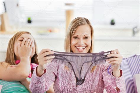 Laughing Women Holding Lingerie Sitting On The Sofa — Stock Photo