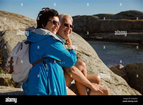 loving mature couple traveling sitting on the rock exploring real man and woman hugging
