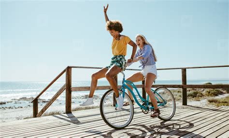Female Friends Having Fun On A Bike At Beach Stock Photo 172119