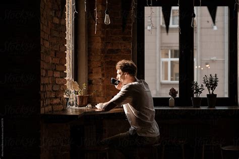 Man Sitting Alone And Drinking Coffee Against Big Window Del