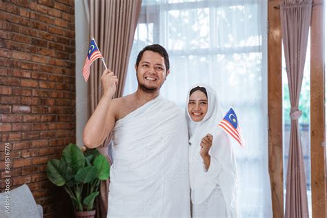 asian wife and husband muslim holding national flag of malaysia hajj and umrah foto de stock