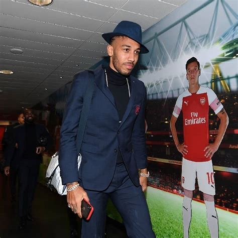 A Man In A Suit And Hat Standing Next To A Poster