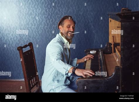 Brutal Man With A Beard 40 Years Old Plays The Old Piano Stock Photo