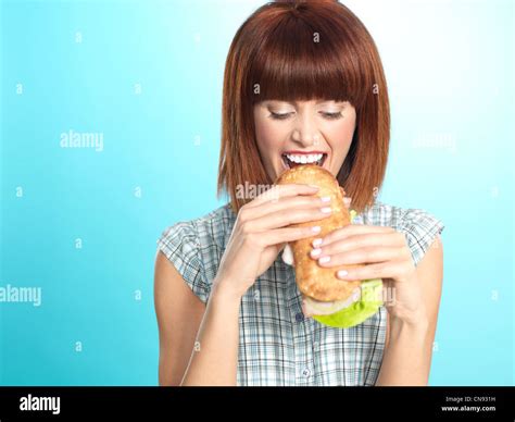Closeup Portrait Of Beautiful Young Woman Eating A Big Sandwich Smiling On Blue Background