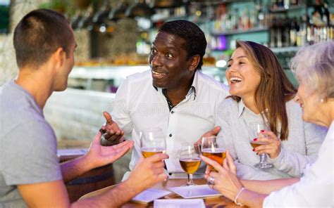 Company Of Multiracial Friends Drinking Beer And Talking With Each