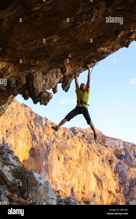 Male Rock Climber Hanging On Roof Of Cave While Climbing Stock Photo
