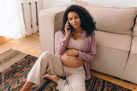 Pretty Pregnant Black Woman Talking On Phone With Her Doctor Smiling